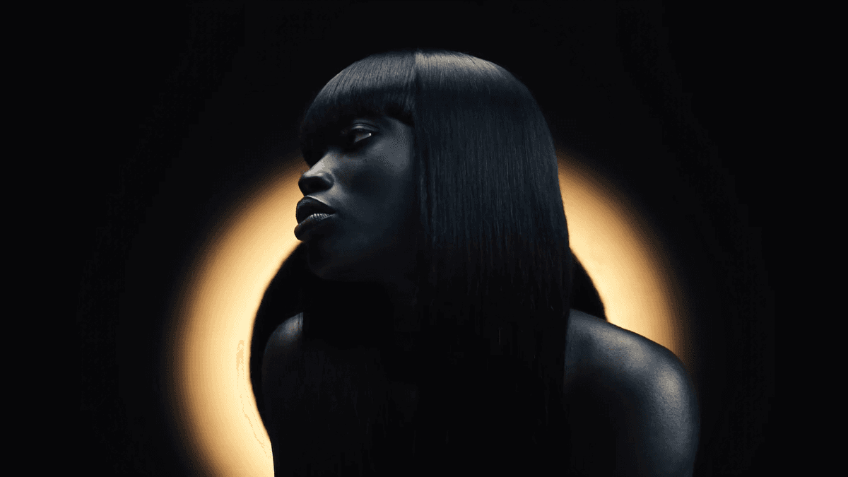 Black woman wearing Mane Logiq Alicia Natural Black wig, dramatic studio lighting
